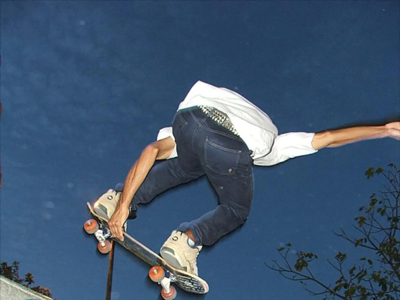 In this image I can see a person is in the air and holding a skateboard. At the bottom of the image...