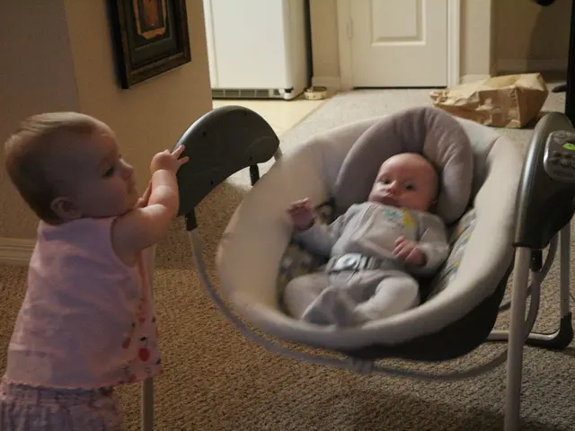 In the center of the image we can see a baby in a baby cradle with button placed on the ground. On...